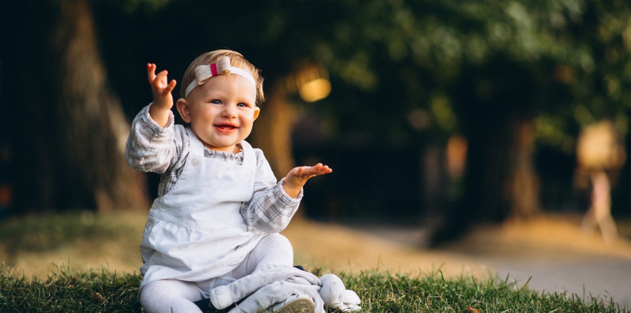 Toddler girl sitting on grass in park